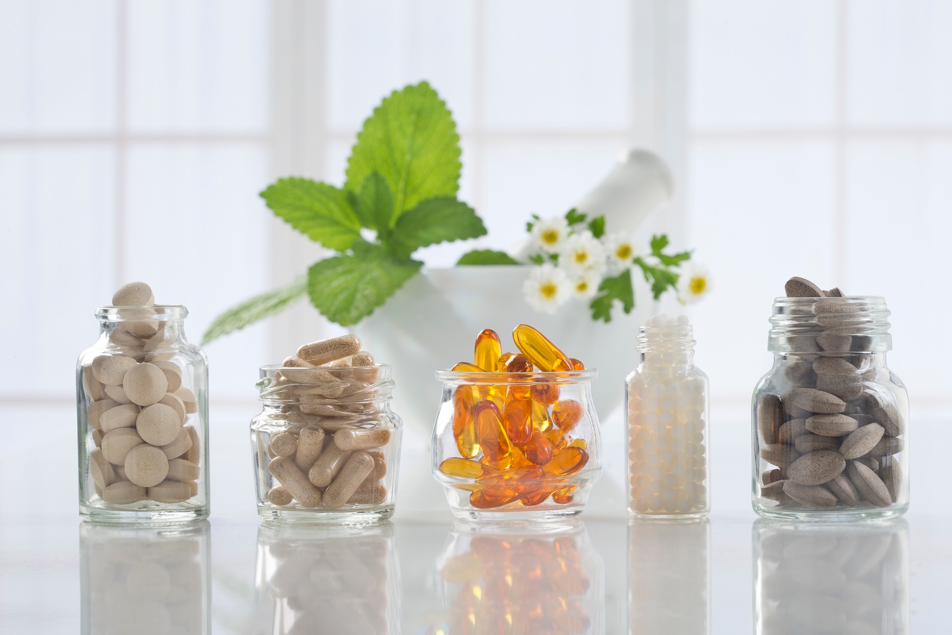 Herbal medicine pills and mortar over bright  background